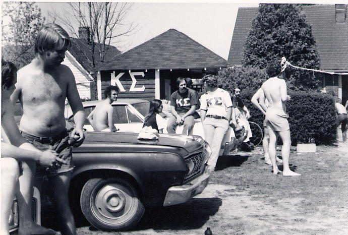 Black and white photograph of brothers washing a car in front of the house