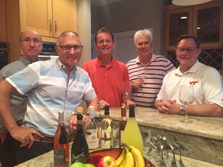 Five brothers leaning on a kitchen counter with wine glasses and bottles