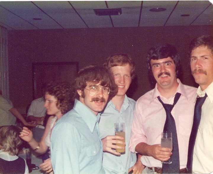 Four brothers in shirts and ties with drinks at a party